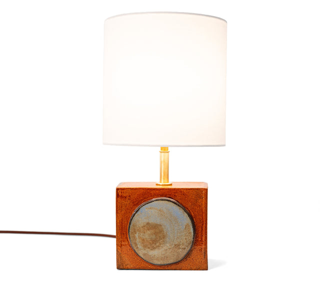 Geometria brick lamp 1, a blue-grey disc set into rust glazed stoneware, brass stem and fabric shade, by Jim Schatz, J Schatz