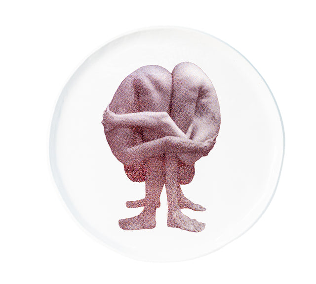 Brown oxide transfer of a seated figure with knees drawn up and arms wrapped on stoneware Gestures plate, J Schatz.