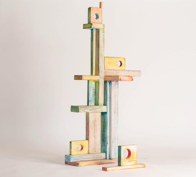 Small standing wood sculpture of figures gathered close, painted in soft washes, J Schatz