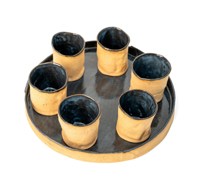Detail of round stoneware tray and cups showing raw speckled clay and glaze drips, J Schatz